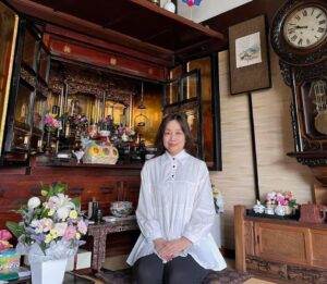 お供えや献花で飾られた仏壇の前に座るわたし